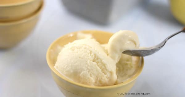 A spoon taking out a bite of ice cream from the bowl.