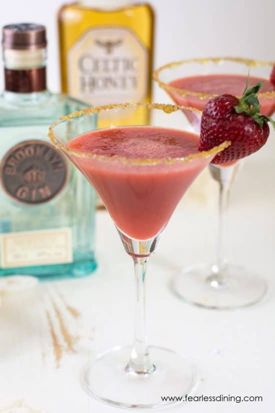 Two martini glasses with strawberry ginger cocktails. Strawberries garnish the glasses.