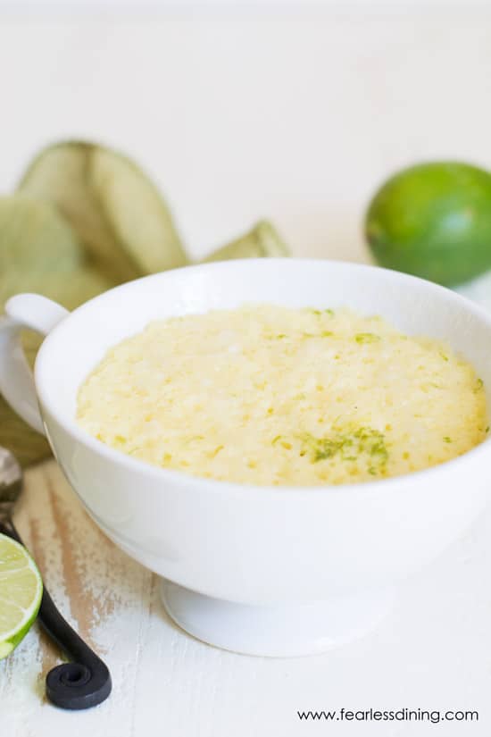 Microwave gluten free mug cake is in a white mug with fresh limes.