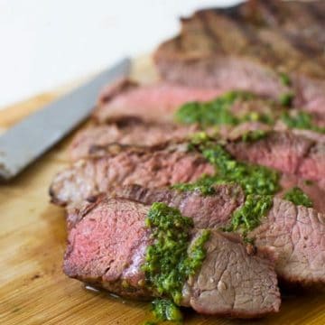 A sliced NY strip steak topped with basil garlic sauce.
