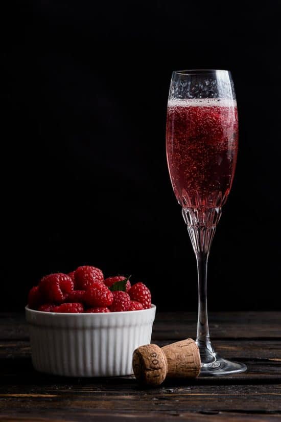 Rose French Cocktail with a bowl of raspberries next to it.