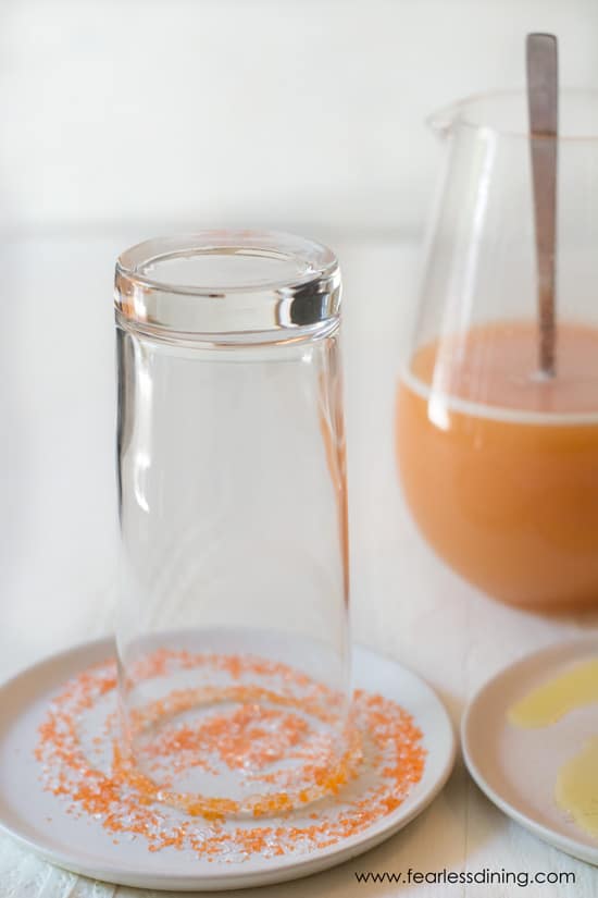 Sugaring the rim of the glass with orange sugar.