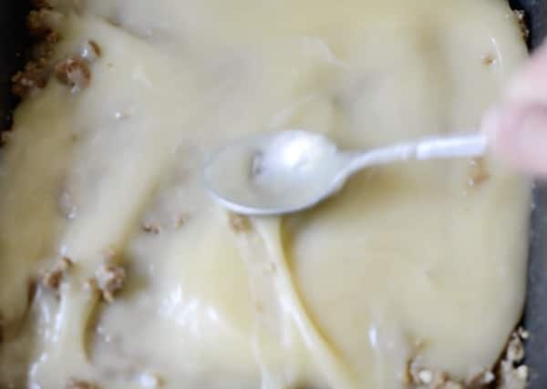 Spreading the condensed milk over the crumb crust.