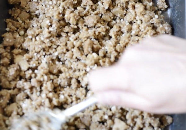 Spreading the graham cracker crust in the 8x8 sized pan.