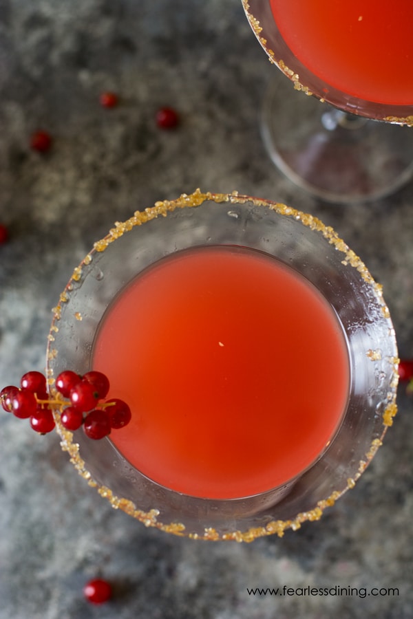 Looking down from the top view of two margarita glasses filled with red currant margaritas. Ginger sugar lines each rim.