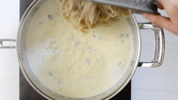 Adding the fettuccine to the cream sauce.