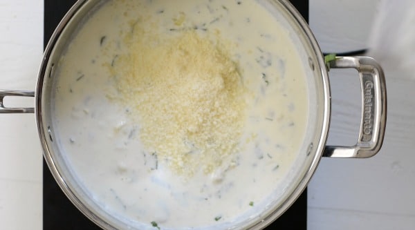 Adding parmesan to cream sauce.