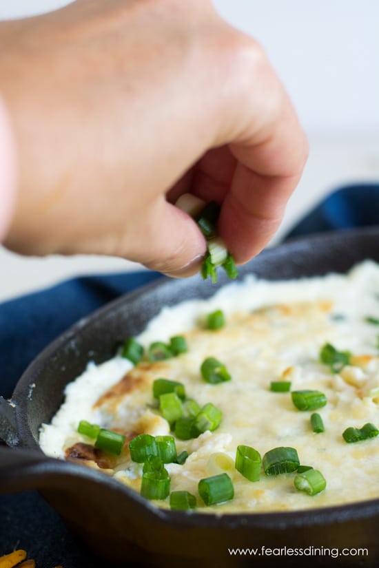 Sprinkling fresh chopped scallions on top of the cheese dip.