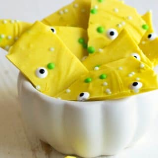 Pieces of turmeric candy overflowing a white candy dish.