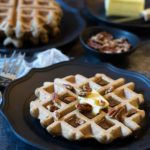 black plate with Banana Flour Waffles garnished with pecans