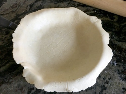 A circle of gluten free galette dough placed into a cast iron skillet.