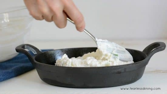 Spreading out the cheese mixture in a black baking dish.