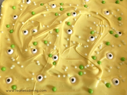 Adding sprinkles and googly eyes to the melted chocolate bark
