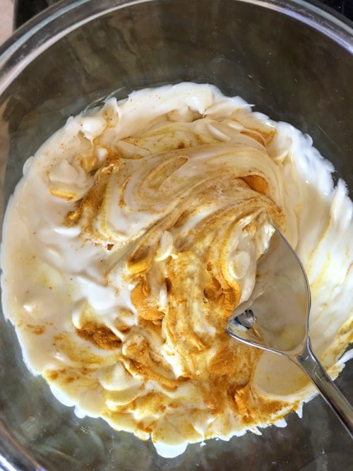 A photo of melted white chocolate and turmeric getting mixed together.