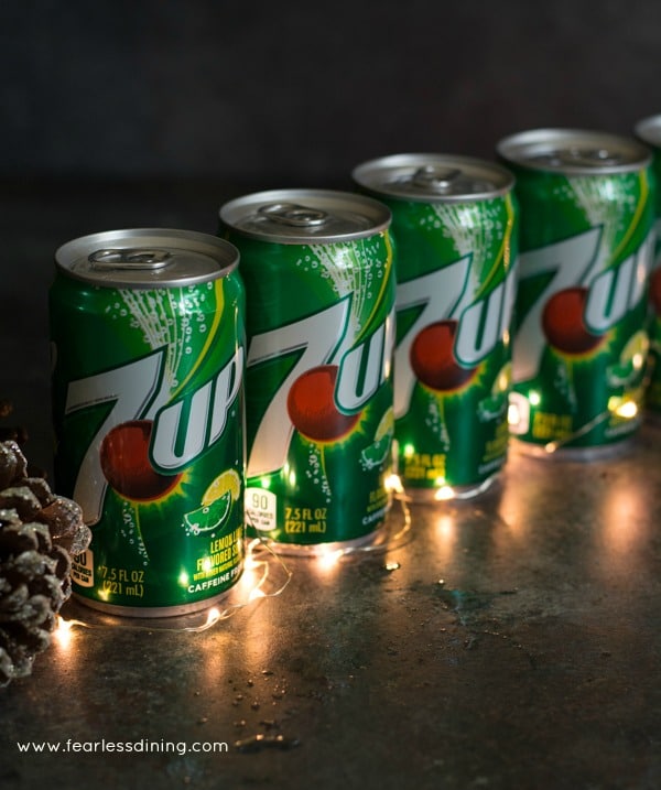 Cans of 7UP lined up with holiday lights.