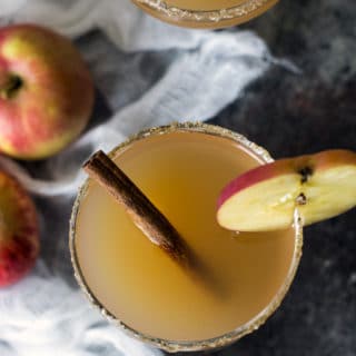 The top view of two apple cider cocktails. The glasses are garnished with apple slices.