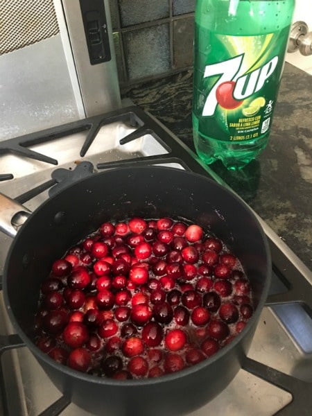 Cranberries cooking in a pot. A bottle of 7UP is behind the pot