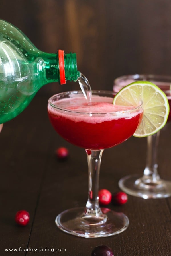 7UP soda being poured into a cranberry rum cocktail