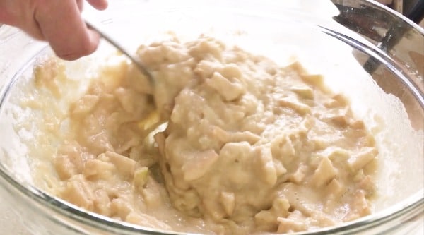 Stirring apple cake batter in a bowl.