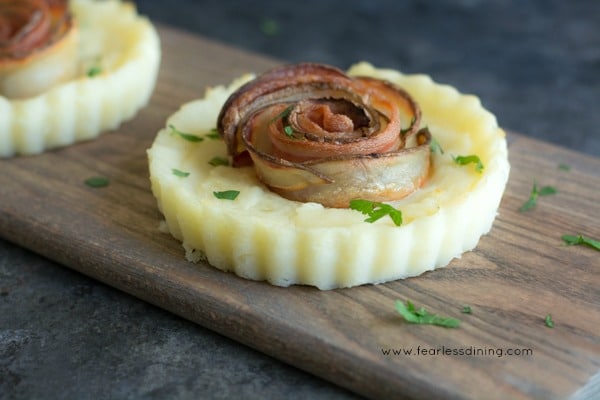 Two mashed potato pies with crispy bacon roses in the middle of each pie