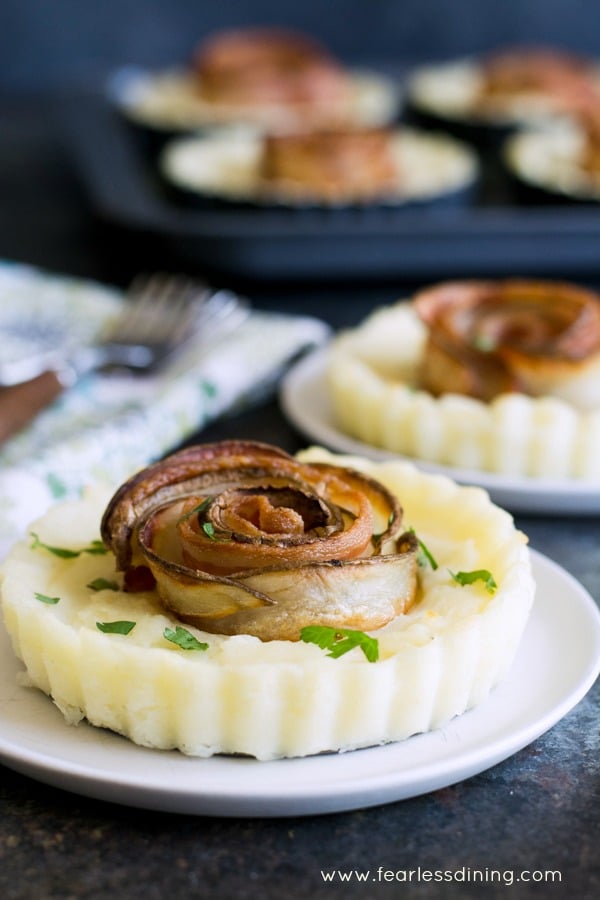 Potato rose tarts on plates. The baking tray is in the background.