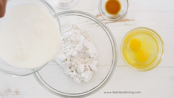 Pouring coconut milk into a bowl of dry ingredients to make crepes batter.