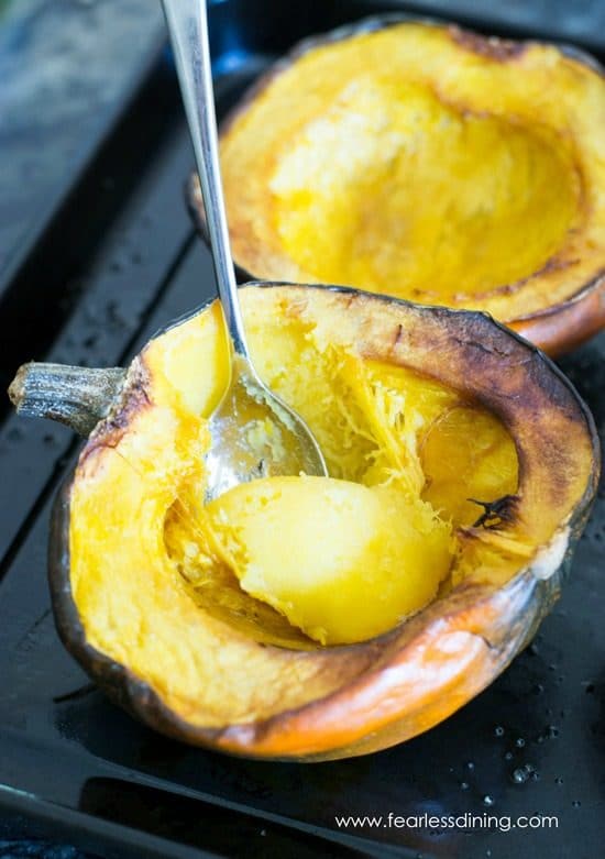 Roasted halves of acorn squash on a baking tray.