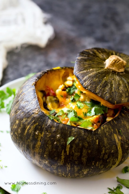 A roasted kabocha squash stuffed with corn, tomatoes, black bean, peppers, and melted cheeses.