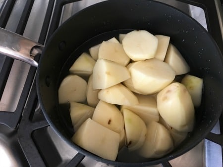 Chopped raw potatoes in a pot about to be cooked.