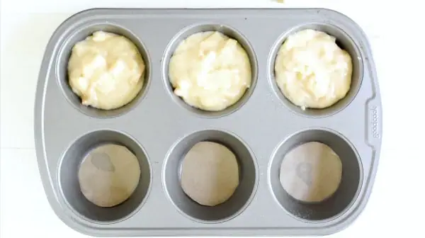 a baking pan with apple cake batter in each cup