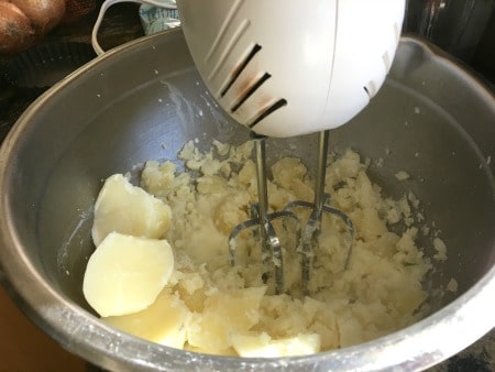 An electric mixer whipping potatoes.