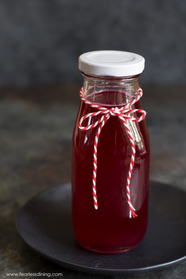 A jar of prickly pear fruit syrup. The jar has a red and white string tied in a bow around it.