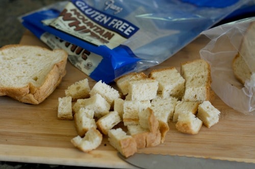 Cubes of bread on a wooden cutting board.