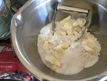 Using a pastry blender to cut cold butter into flour.