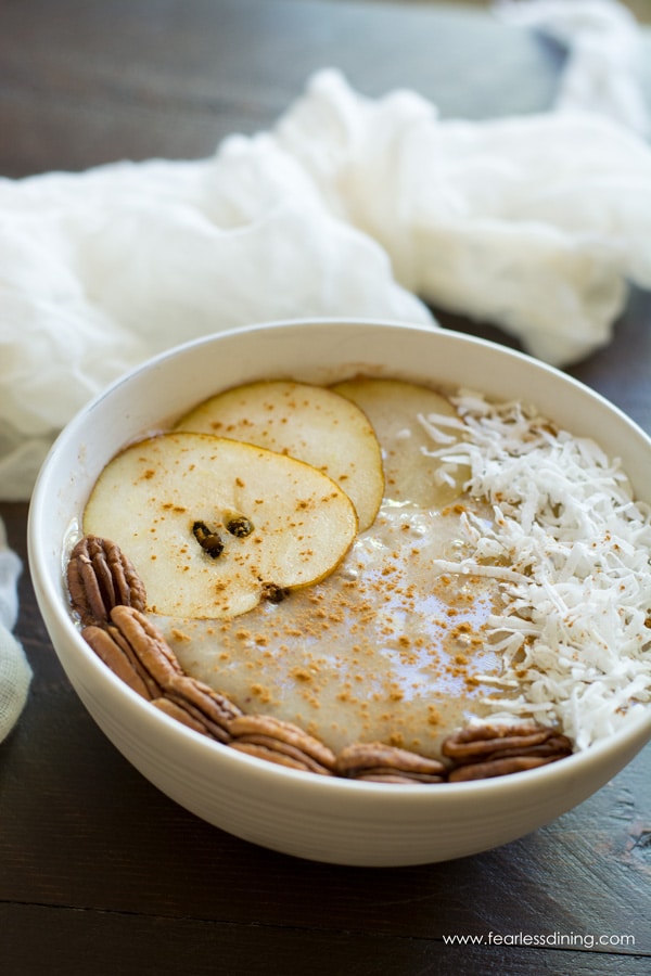 Creamy pear smoothie bowl with sliced pears, pecans, and shredded coconut on top.