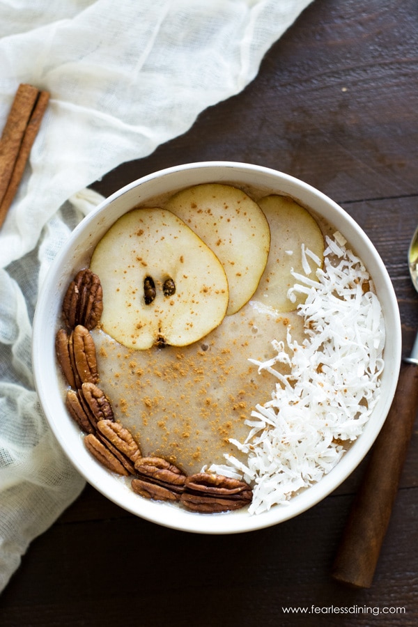 Top view of a pear smoothie bowl. The smoothie is topped with pear slices, pecans and shredded coconut.