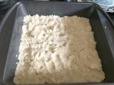 Pressing the shortbread crust into the 8x8 baking pan.