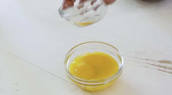 pouring the oil into the egg yolks