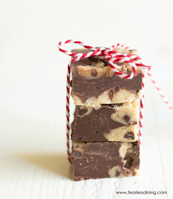 A stack of chocolate fudge with cookie dough chunks. The stack is tied with a red and white string