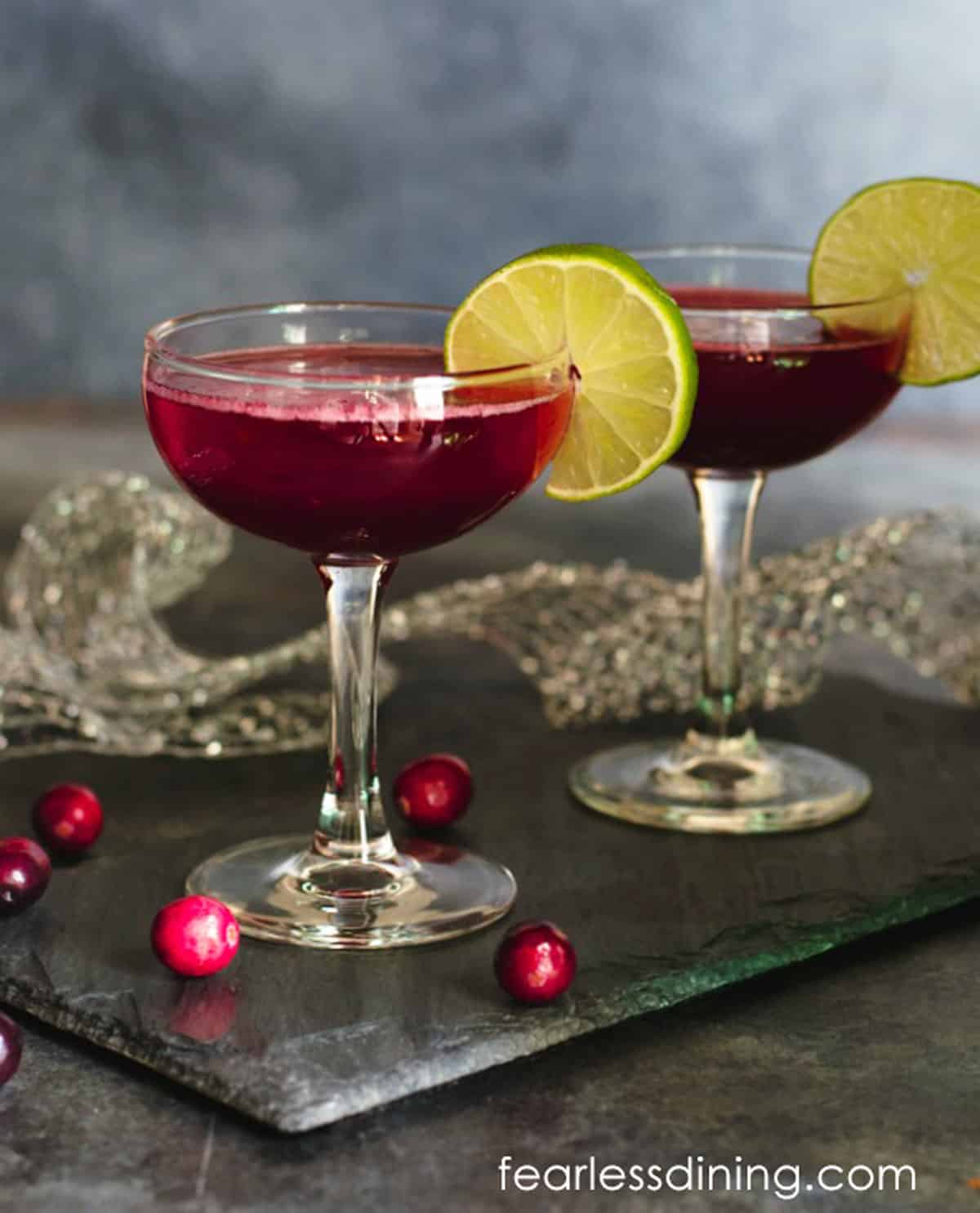 Two glasses of cranberry cocktail on a slate serving dish.