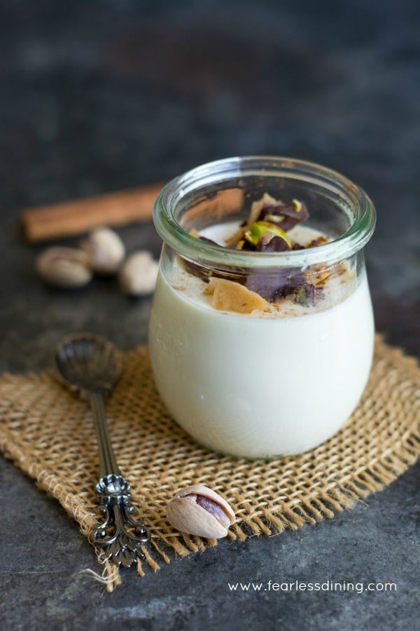 Eggnog panna cotta in a jar. It is topped with pistachios and toffee.