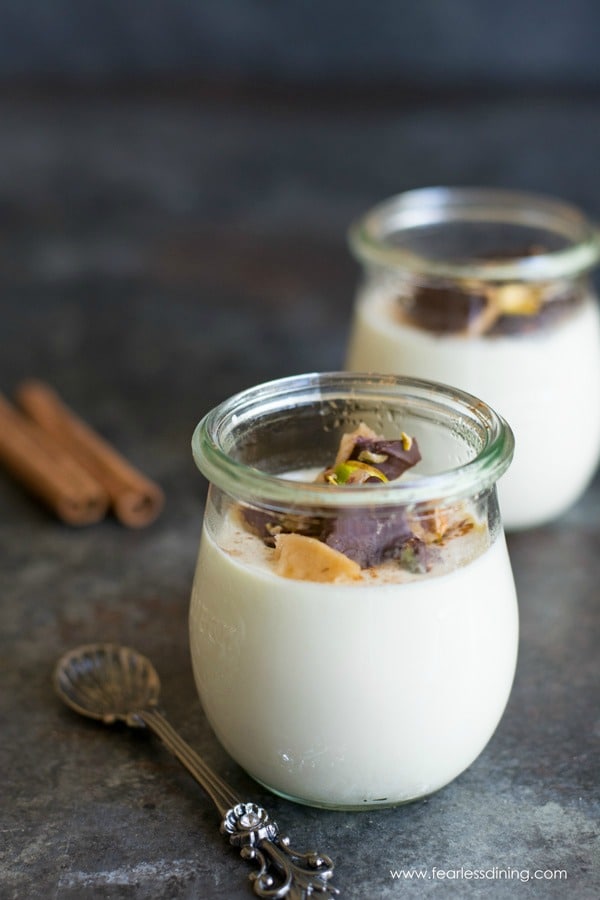 Two jars of eggnog panna cotta. Each is topped with homemade toffee pieces.