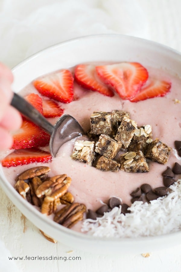A spoon dipping into the strawberry smoothie bowl.