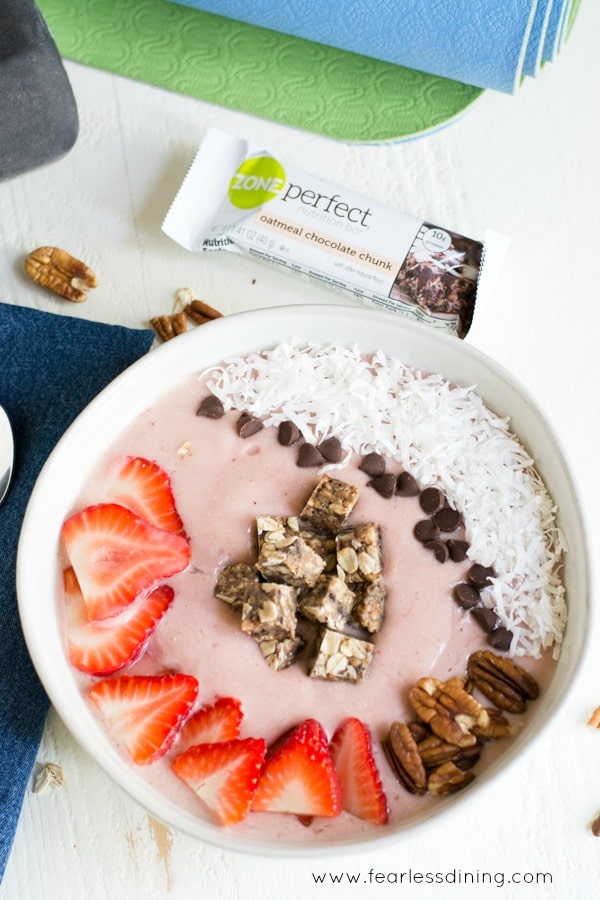 A smoothie bowl next to a protein bar.