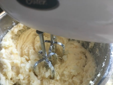 Using an electric mixer to whip the potatoes.