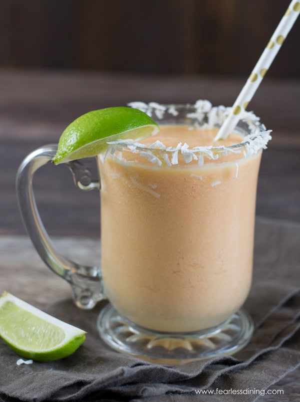 paypaya pineapple smoothie in a glass mug with sliced limes
