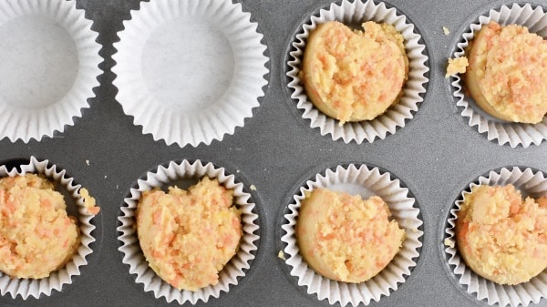 putting muffin batter into a lined muffin tin
