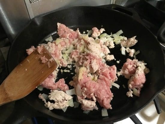 Cooking ground turkey with onion in a cast iron skillet.