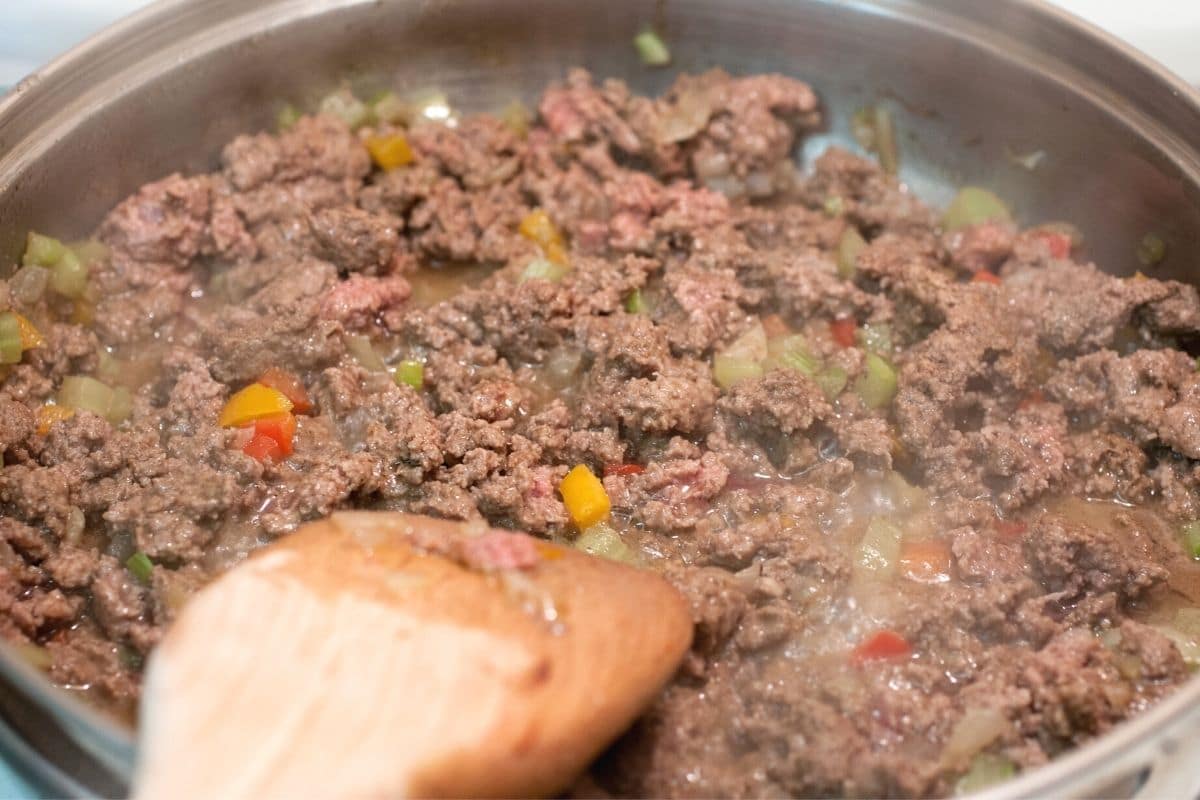 Browning onion, ground beef, and peppers in a skillet.