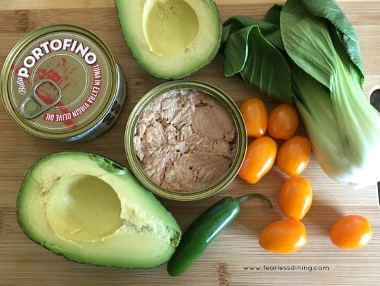 An open can of tuna with bok choy, avocado and cherry tomatoes.
